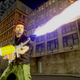 Grand Theft Auto III's anti-hero shoots a flame thrower while standing on a city block.